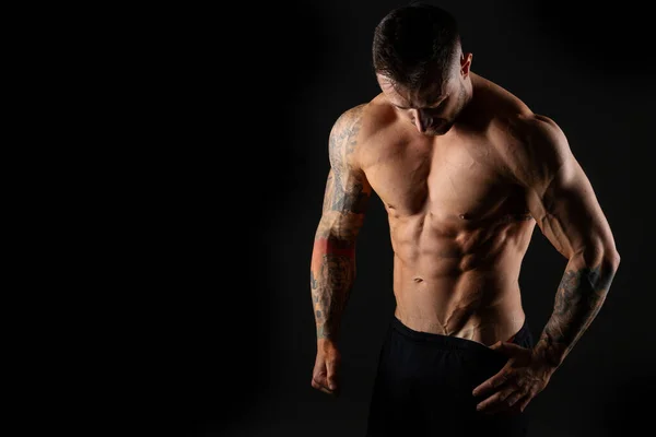 Siyah arka planda yakışıklı kaslı erkek vücut geliştirici. Güçlü adam..