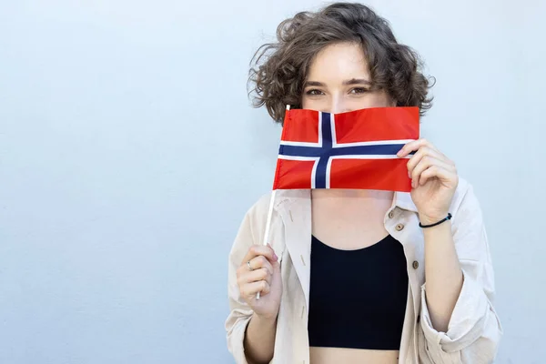 美丽的女人 卷曲的头发 挂着挪威国旗 她的脸被一面灰色的墙挡住了 — 图库照片
