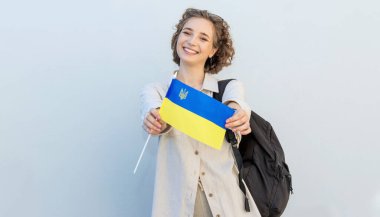 Young happy student woman with the flag of Ukraine and backpack. Independence Day Ukraine.  clipart