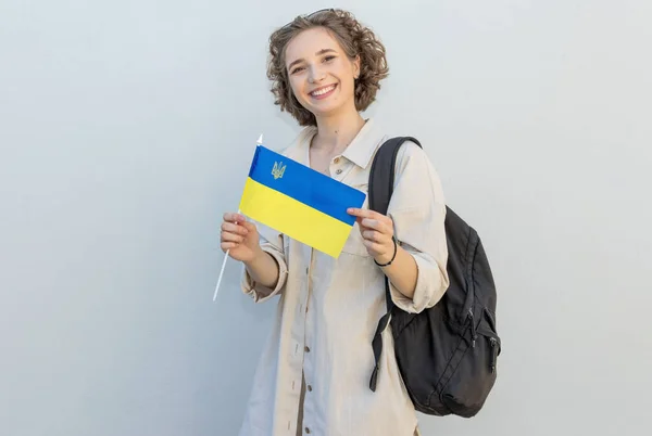 年轻快乐的女学生 拿着乌克兰国旗和背包 背靠一堵轻墙和一个自由的文字空间 乌克兰独立日 — 图库照片
