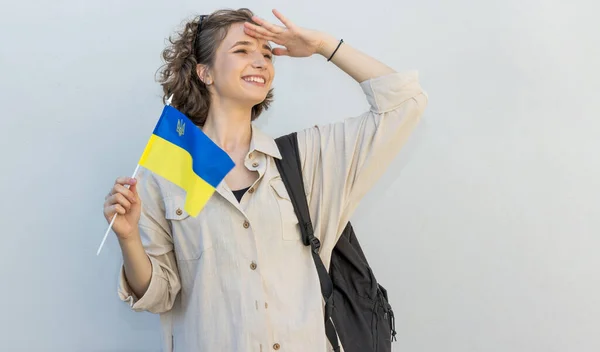 拿着乌克兰国旗和背包的年轻女子站在自由空间的一侧 — 图库照片