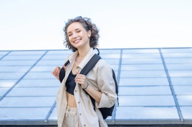 Sırt çantalı genç bayan öğrenci kameraya bakıyor..