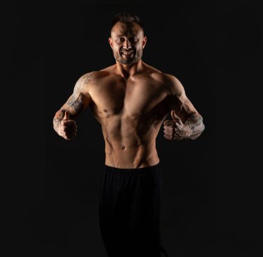 Karın kaslarına, pazılara ve arka planda trisepslere koçluk yaptıktan sonra ideal vücutlu yakışıklı bir vücut geliştirici..