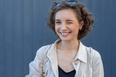 Güzel bir kızın yakın plan portresi kıvırcık saçlı ve kameraya bakıyor..