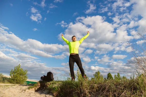 Muscular man in sportswear is engaged in the morning fitness in nature.