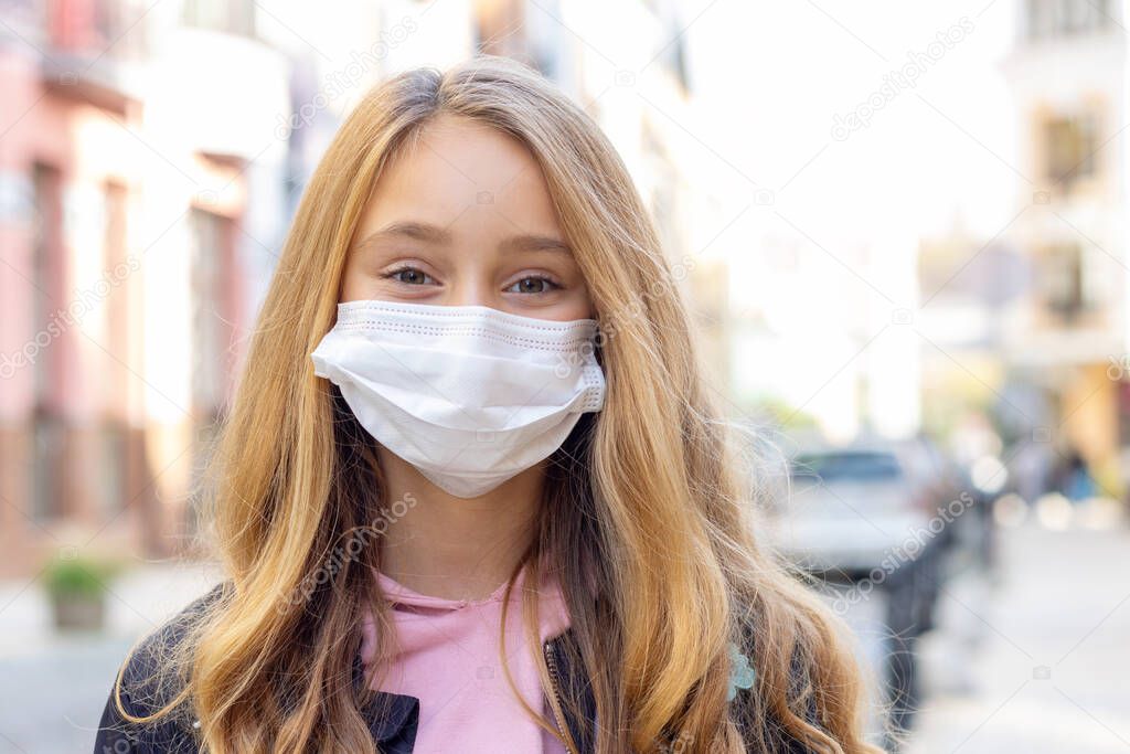Quarantine. Close up portrait little girl 8 years old wearing protective mask for good air outdoor. Coronavirus concept.