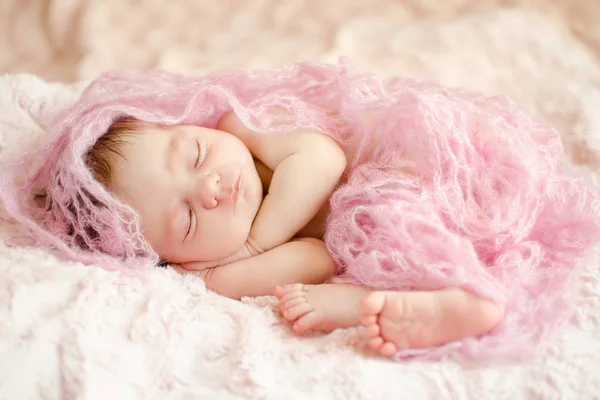 柔らかいふわふわの敷物の上に横たわるニット素材に包まれて眠っている新生の女の赤ちゃん — ストック写真