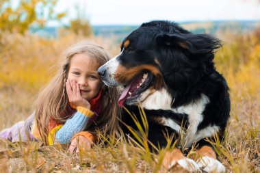 Kız köpekle nın Sennenhund sonbahar çim üzerinde yalan