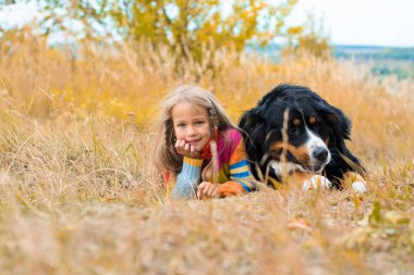 Kız köpekle nın Sennenhund sonbahar çim üzerinde yalan