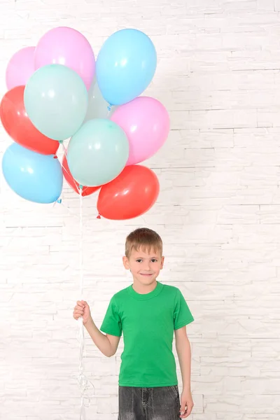 Chłopiec Zielony Shirt Gospodarstwa Mnóstwo Kolorowych Balonów Przeciwko Białym Murem — Zdjęcie stockowe