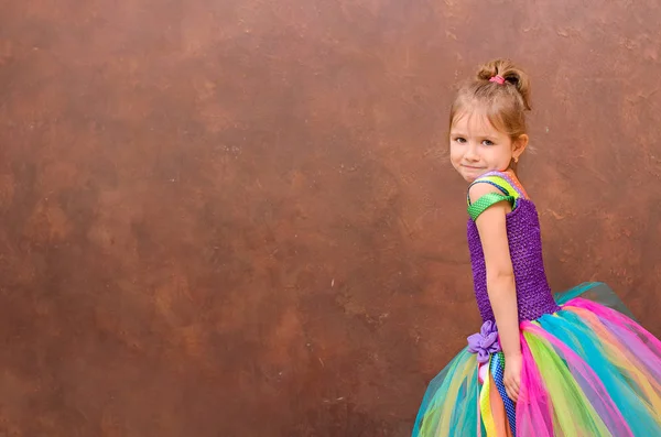 Dziewczyna Kolorowy Strój Uśmiechający Się Tle Ściany Brązowy — Zdjęcie stockowe