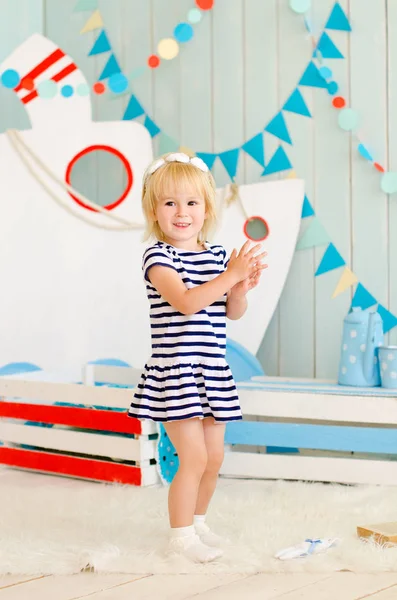 Blond Meisje Een Gestreepte Jurk Staat Een Decoratieve Achtergrond Schip — Stockfoto