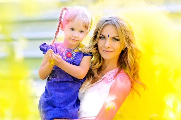 神聖な黄色のペンキの雲に両腕で彼女の娘を持つお母さん — ストック写真