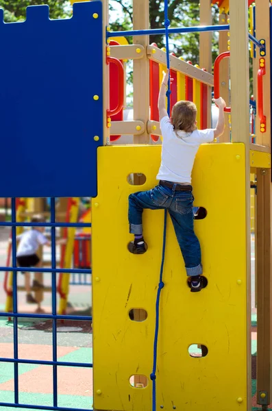 Teenager climbs on the playground in the park in the summer