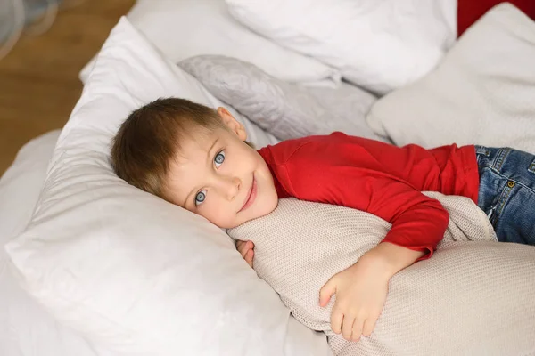 Handsome Light Eyed Boy Red Jumper Lies White Pillows Blankets — Stock Photo, Image