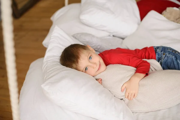 Handsome Light Eyed Boy Red Jumper Lies White Pillows Blankets — Stock Photo, Image