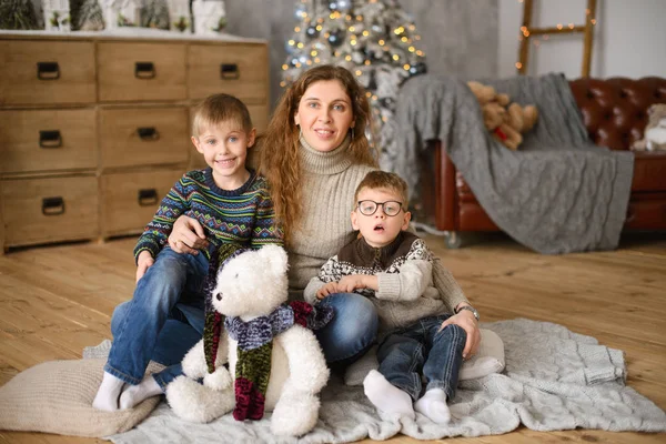 Máma Dvěma Syny Svetrech Objímání Sedící Dřevěné Podlaze Pokoji Vánočním — Stock fotografie