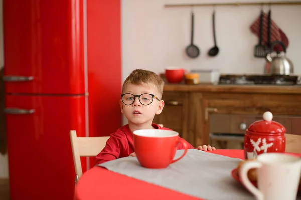 Niño Pequeño Gafas Sentado Mesa Comedor Que Levanta Taza Roja — Foto de Stock