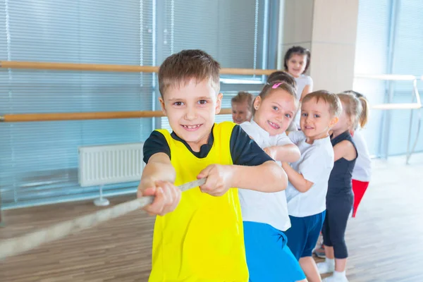 Děti a rekreace, skupina happy mnohonárodnostní školy děti hrají přetahování provazem v tělocvičně — Stock fotografie