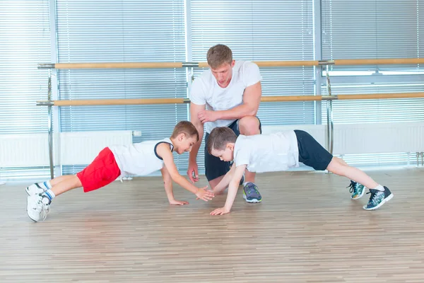 一群孩子在健身房和老师一起做孩子体操。快乐运动的孩子在健身房。酒吧锻炼。木板. — 图库照片