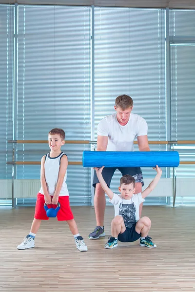 Grupo de niños haciendo gimnasia infantil en el gimnasio con el profesor. Niños deportistas felices en el gimnasio. rodillo de espuma — Foto de Stock