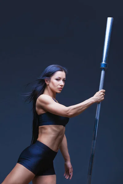 Brutal atlética sexy mujer sostiene una barra. El concepto de deportes de ejercicio, la publicidad de un gimnasio.Aislado sobre un fondo negro . — Foto de Stock