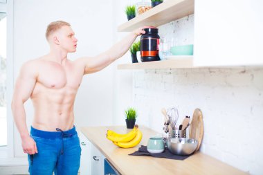 Çıplak bir gövde mutfak sağlıklı beslenme kavramı ile bir spor beslenme protein ve muz, kaslı adam. Atletik yaşam tarzının.