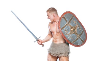 Kılıç ve kalkan beyaz arka plan üzerinde izole poz vücut geliştirmeci adam. Ciddi gömleksiz adam mascular vücudunu gösteren.