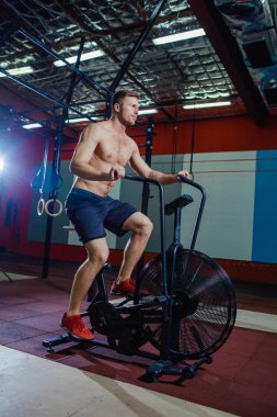 Spor salonunda egzersiz bisikleti kullanan genç adam uygun. Kardiyo egzersiz spor eğitim çapraz için hava bisiklet kullanarak fitness erkek.