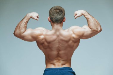 .vücut geliştirmeci poz. Güzel sportif adam erkek güç. Fitness mavi şort ve güneş gözlüğü kaslı. izole gri arka plan üzerinde. Kas gövde olan adam. Güçlü atletik erkek Fitness modeli gövde