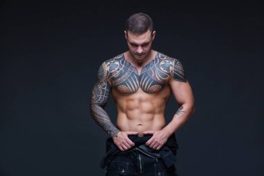 Bir kaslı çıplak gövde koyu arka plan üzerine dövmeli olan adam. ABS