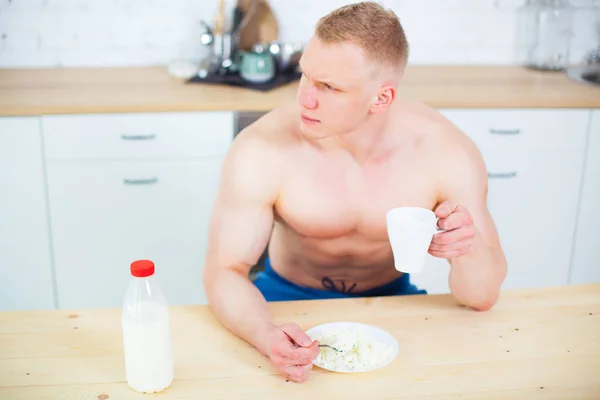 Svalnatý muž nahý trup v kuchyni s mlékem a tvarohem, koncept zdravé stravy. Sportovní způsob života. — Stock fotografie