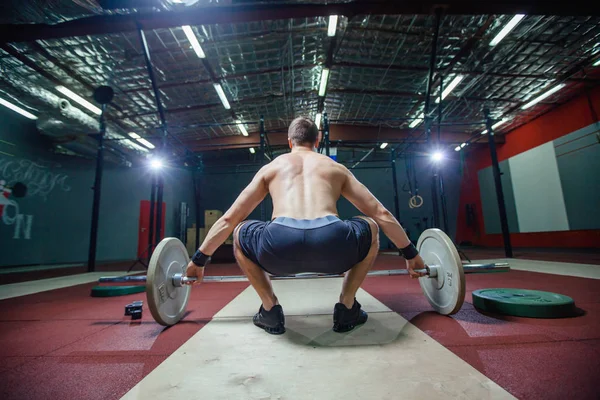 Muskulöser Fitness-Mann bereitet sich darauf vor, in einem modernen Fitness-Center eine Langhantel über den Kopf zu heben.. — Stockfoto