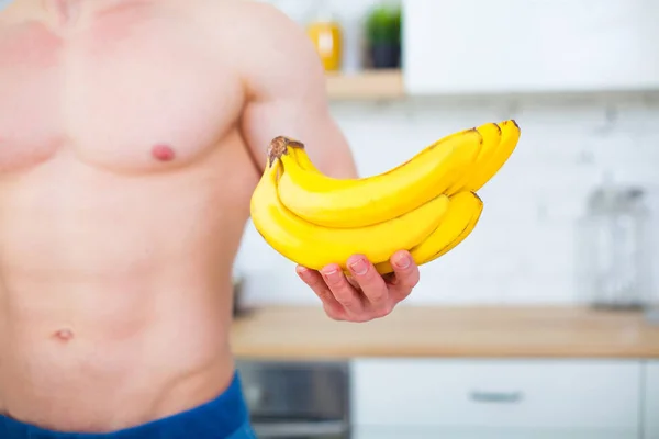 과일, 건강 한 식 생활의 개념을 가진 부엌에서 벌 거 벗은 상체와 함께 근육 질 남자. 생활의 운동 방법입니다. 바나나 클로즈업. — 스톡 사진