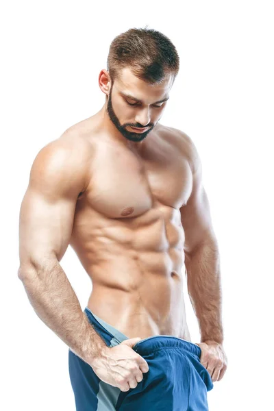 Bodybuilder poseren. Mooie sportieve vent mannelijke kracht. Fitness gespierd in blauwe shorts. op geïsoleerde witte achtergrond. Man met gespierde torso. Sterke atletische Man Fitness Model Torso weergegeven: zes pack abs — Stockfoto