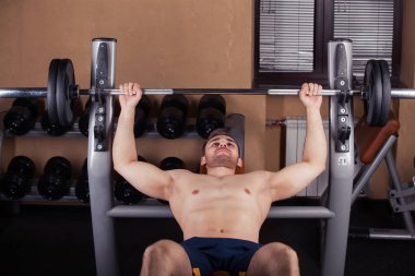 Zalim atletik adam göğüs presinde kaslarını şişiriyor.
