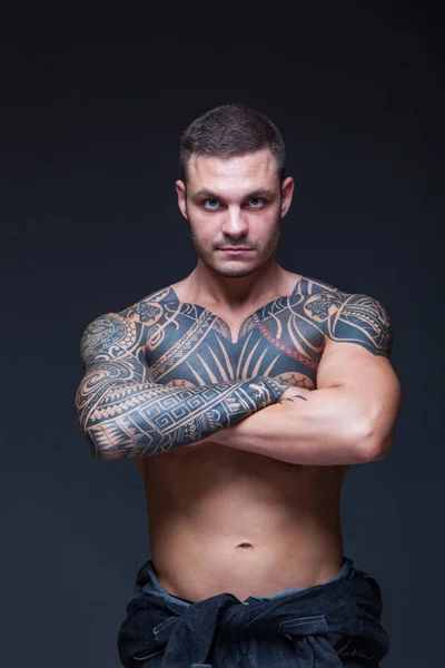 Mannen med en muskulös nakna torso med tatueringar på den mörka bakgrunden. ABS — Stockfoto