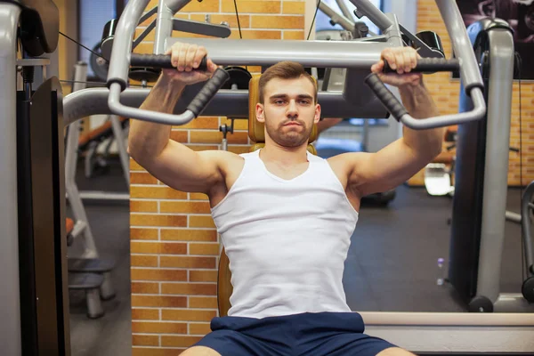 Muž cvičí v tělocvičně. Fitness sportovec dělá hrudní cvičení na vertikální lavice lisovací stroj — Stock fotografie