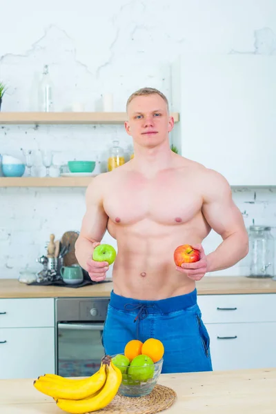 Muskularny mężczyzna z nagi tors w kuchni z owoców, pojęcie zdrowego odżywiania. Sportowy styl życia. — Zdjęcie stockowe