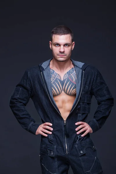 El hombre con un torso muscular con tatuajes en el fondo oscuro — Foto de Stock