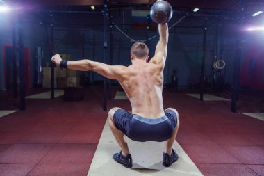 Çapraz Eğitim uygun. Fitness adam iş ağırlık terbiye kettlebell kaldırarak. Genç atlet kettlebell yapıyor salıncaklar. Vücut geliştirmeci kaldırma kettlebell. Çapraz eğitmen spor salonunda uygun. Spor salonunda çapraz