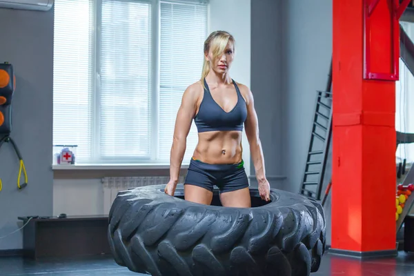Kadın atlet dönüm büyük bir lastik ile çalışma dışarı uygun ve spor salonunda taşırlar. Crossfit kadın ile büyük lastik egzersiz