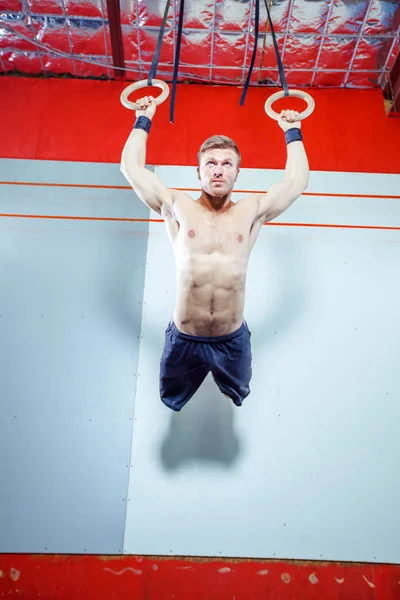 Jimnastik halkaları üzerinde spor salonunda egzersiz kas-up egzersiz yoğun yapan genç erkek çapraz yerleştirmek. — Stok fotoğraf