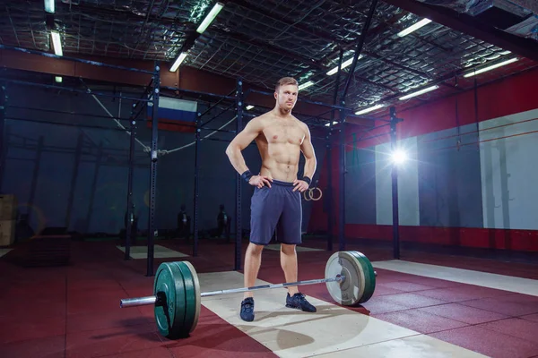 Porträt eines muskulösen Mannes beim Training mit der Langhantel im Fitnessstudio. steht neben der Theke und ruht sich aus. — Stockfoto