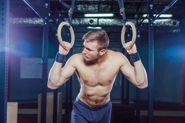 Muskulöser Kerl bei der Übung an den Ringen — Stockfoto