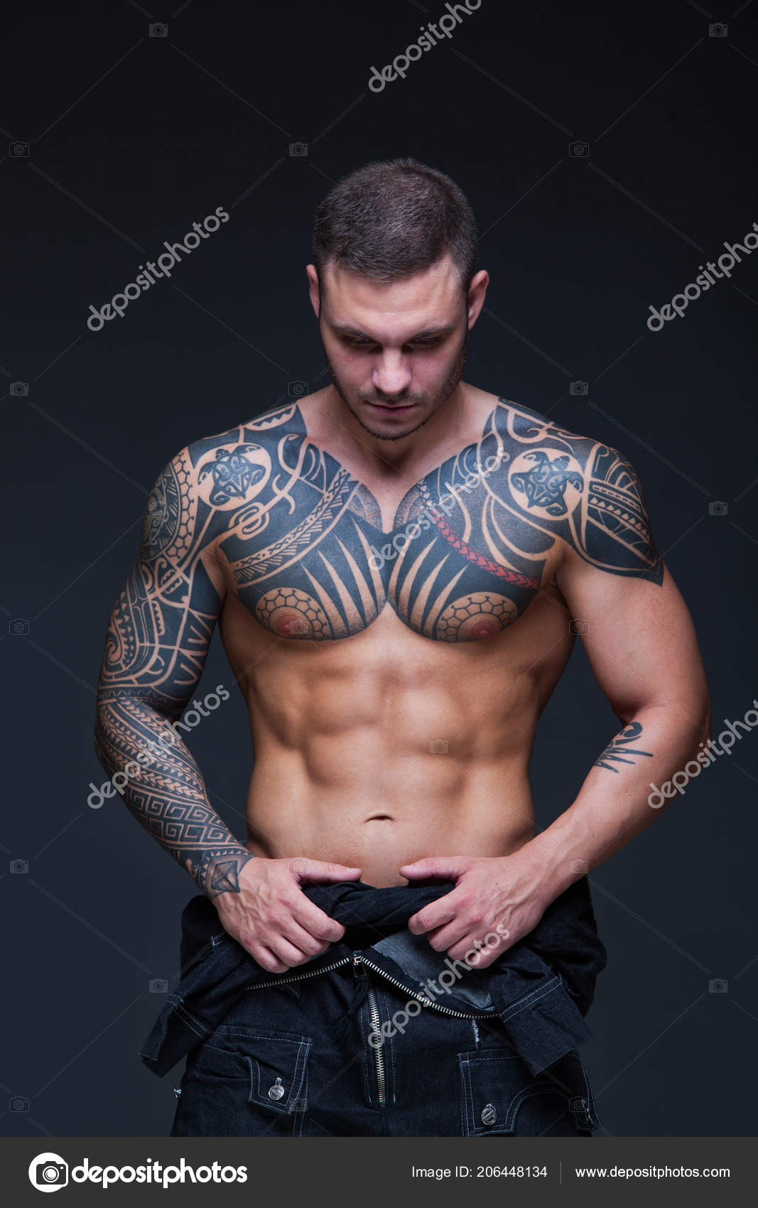 The man with a muscular naked torso with tattoos on the dark background. ABS Stock Photo by