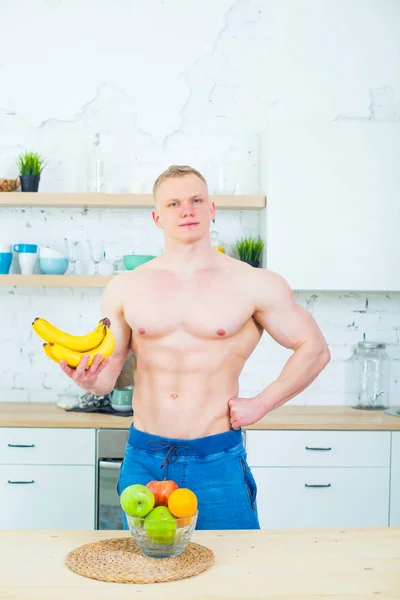 Kaslı adam meyve, sağlıklı beslenme kavramı ile mutfakta çıplak bir gövde ile. Atletik yaşam tarzının. — Stok fotoğraf