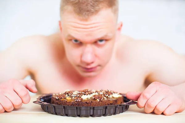 Homem musculoso com um tronco nu na cozinha com torta, o conceito de uma dieta saudável. Estilo de vida atlético. A tentação de doce . — Fotografia de Stock