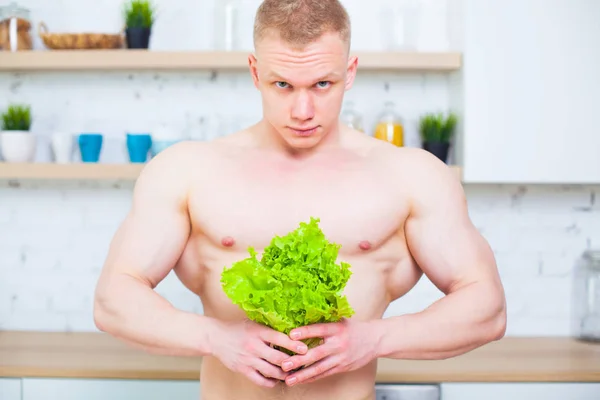 肌肉发达的男人带着一个裸体的躯干在厨房里用沙拉, 健康饮食的概念。运动的生活方式. — 图库照片