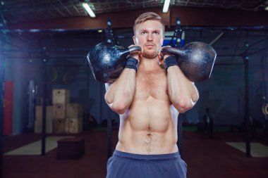 Çapraz Eğitim uygun. Fitness adam iş ağırlık terbiye kettlebell kaldırarak. Genç atlet kettlebell yapıyor salıncaklar. Vücut geliştirmeci kaldırma kettlebell. Çapraz eğitmen spor salonunda uygun. Spor salonunda çapraz